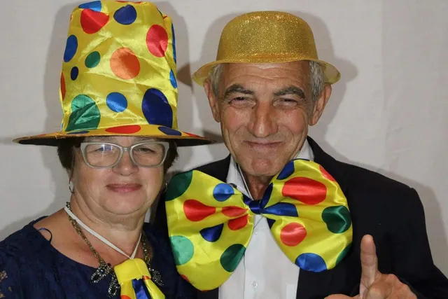 Pareja de invitados con sombreros y una pajarita gigante de lunares del atrezzo