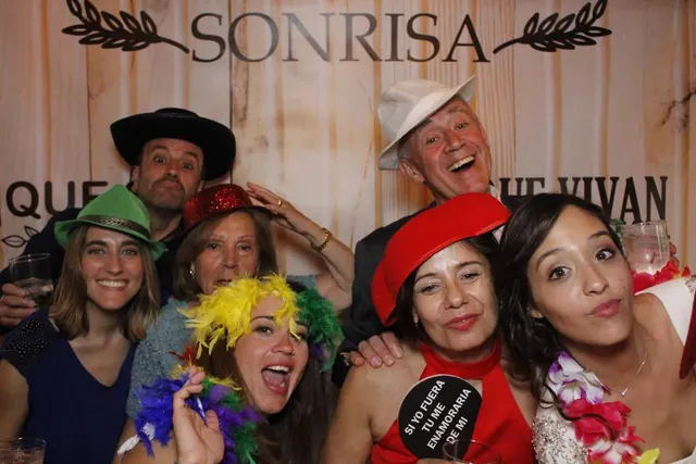 Grupo de invitados con sombreros y boas de plumas posando juntos en una boda