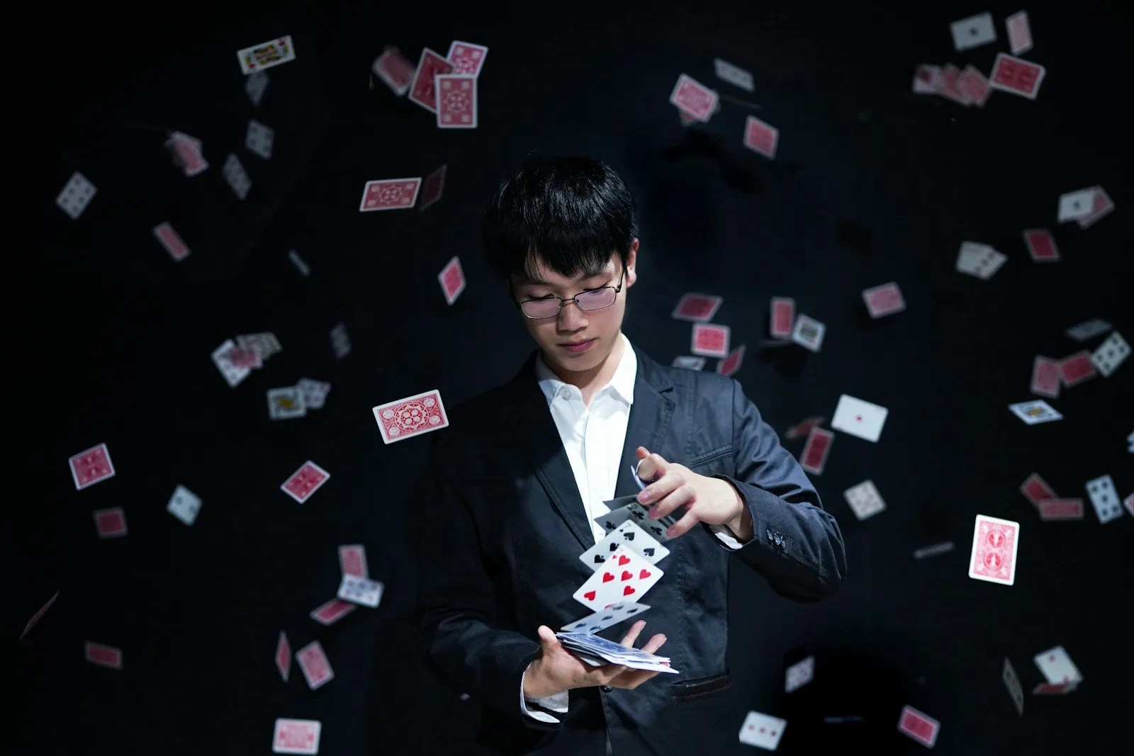 Mago haciendo un truco de cartas con la baraja volando a su alrededor